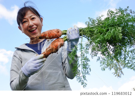 拿著收穫的胡蘿蔔的中年婦女 119683012