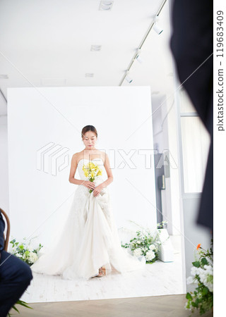 Small wedding - the priest is present, the bride and groom hold their wedding bouquets, hold hands, and share a beautiful moment with family and friends. 119683409