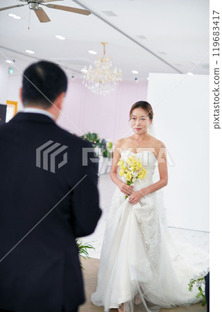 Small wedding - the priest is present, the bride and groom hold their wedding bouquets, hold hands, and share a beautiful moment with family and friends. 119683417