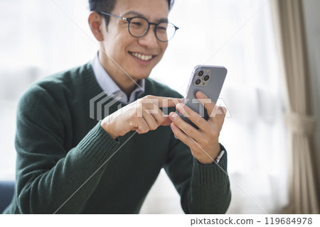 一名 30 多歲男子的手拿著智慧型手機 119684978