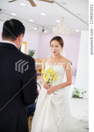 Small wedding - the priest is present, the bride and groom hold their wedding bouquets, hold hands, and share a beautiful moment with family and friends. Small wedding - the priest is present, the bride and groom hold their wedding bouquets, hold hands, and share a beautiful moment with family and friends. 119685851