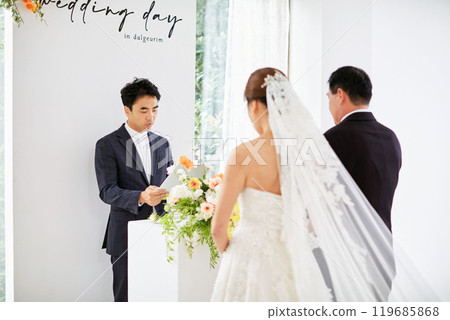 Small wedding - the priest is present, the bride and groom hold their wedding bouquets, hold hands, and share a beautiful moment with family and friends. Small wedding - the priest is present, the bride and groom hold their wedding bouquets, hold hands, and share a beautiful moment with family and friends. 119685868