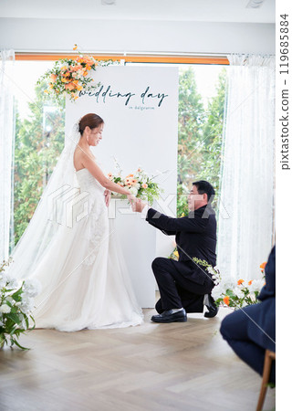 Small wedding - the priest is present, the bride and groom hold their wedding bouquets, hold hands, and share a beautiful moment with family and friends. 119685884