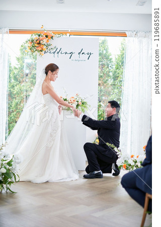 Small wedding - the priest is present, the bride and groom hold their wedding bouquets, hold hands, and share a beautiful moment with family and friends. Small wedding - the priest is present, the bride and groom hold their wedding bouquets, hold hands, and share a beautiful moment with family and friends. 119685891