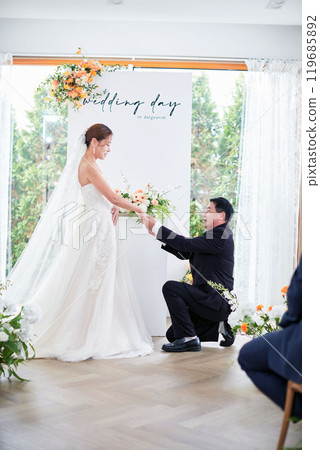 Small wedding - the priest is present, the bride and groom hold their wedding bouquets, hold hands, and share a beautiful moment with family and friends. 119685892