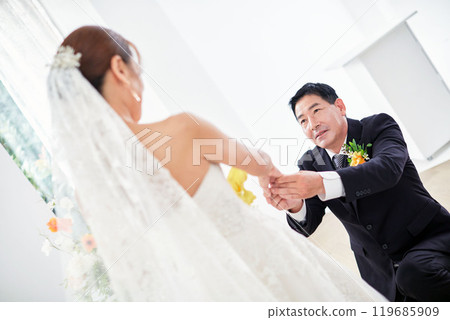 Small wedding - the priest is present, the bride and groom hold their wedding bouquets, hold hands, and share a beautiful moment with family and friends. Small wedding - the priest is present, the bride and groom hold their wedding bouquets, hold hands, and share a beautiful moment with family and friends. 119685909