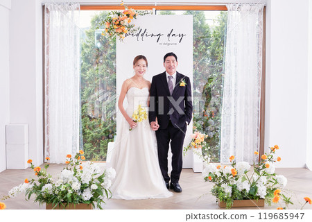 Small wedding - the priest is present, the bride and groom hold their wedding bouquets, hold hands, and share a beautiful moment with family and friends. 119685947