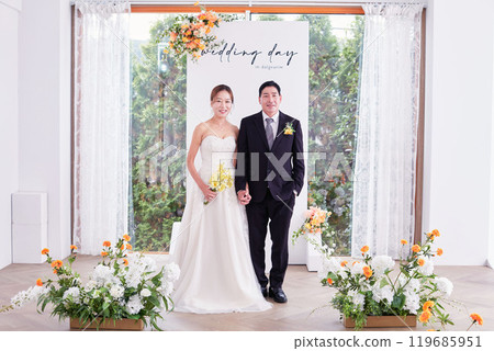 Small wedding - the priest is present, the bride and groom hold their wedding bouquets, hold hands, and share a beautiful moment with family and friends. Small wedding - the priest is present, the bride and groom hold their wedding bouquets, hold hands, and share a beautiful moment with family and friends. 119685951