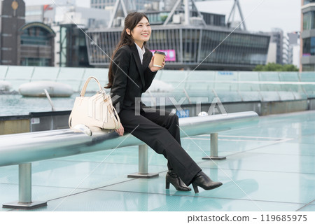 A young businesswoman relaxing with a takeaway coffee in the middle of the city A young businesswoman relaxing with a takeaway coffee in the middle of the city 119685975