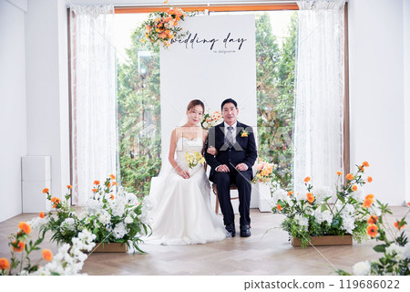 Small wedding - the priest is present, the bride and groom hold their wedding bouquets, hold hands, and share a beautiful moment with family and friends. 119686022