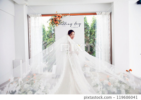 Small wedding - the priest is present, the bride and groom hold their wedding bouquets, hold hands, and share a beautiful moment with family and friends. 119686041