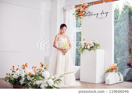 Small wedding - the priest is present, the bride and groom hold their wedding bouquets, hold hands, and share a beautiful moment with family and friends. 119686046