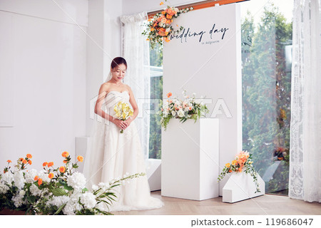 Small wedding - the priest is present, the bride and groom hold their wedding bouquets, hold hands, and share a beautiful moment with family and friends. 119686047