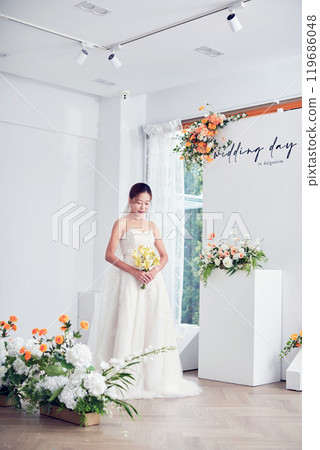 Small wedding - the priest is present, the bride and groom hold their wedding bouquets, hold hands, and share a beautiful moment with family and friends. 119686048