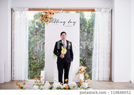 Small wedding - the priest is present, the bride and groom hold their wedding bouquets, hold hands, and share a beautiful moment with family and friends. 119686052