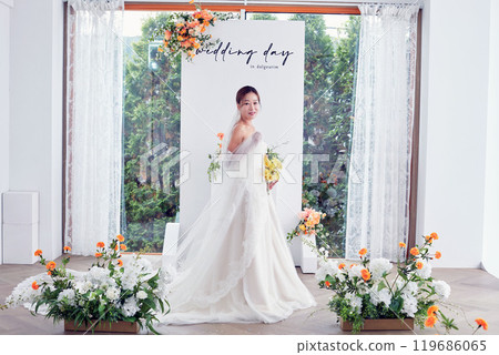 Small wedding - the priest is present, the bride and groom hold their wedding bouquets, hold hands, and share a beautiful moment with family and friends. 119686065