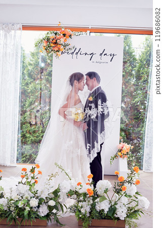 Small wedding - the priest is present, the bride and groom hold their wedding bouquets, hold hands, and share a beautiful moment with family and friends. 119686082