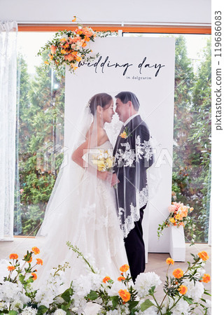 Small wedding - the priest is present, the bride and groom hold their wedding bouquets, hold hands, and share a beautiful moment with family and friends. Small wedding - the priest is present, the bride and groom hold their wedding bouquets, hold hands, and share a beautiful moment with family and friends. 119686083