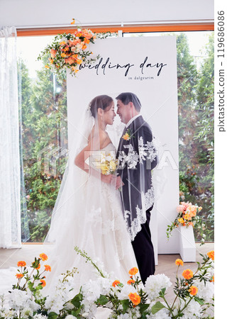 Small wedding - the priest is present, the bride and groom hold their wedding bouquets, hold hands, and share a beautiful moment with family and friends. 119686086