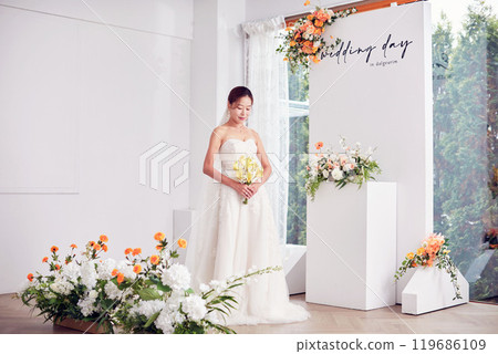 Small wedding - the priest is present, the bride and groom hold their wedding bouquets, hold hands, and share a beautiful moment with family and friends. 119686109