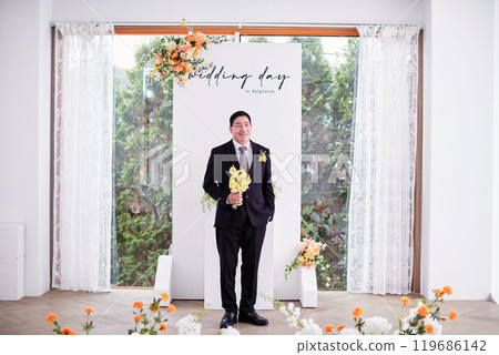 Small wedding - the priest is present, the bride and groom hold their wedding bouquets, hold hands, and share a beautiful moment with family and friends. 119686142