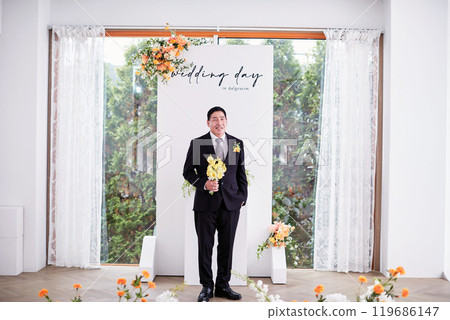Small wedding - the priest is present, the bride and groom hold their wedding bouquets, hold hands, and share a beautiful moment with family and friends. Small wedding - the priest is present, the bride and groom hold their wedding bouquets, hold hands, and share a beautiful moment with family and friends. 119686147