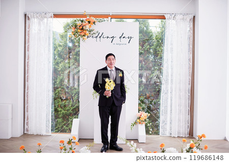 Small wedding - the priest is present, the bride and groom hold their wedding bouquets, hold hands, and share a beautiful moment with family and friends. 119686148