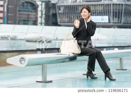 A young businesswoman relaxing with a takeaway coffee in the middle of the city A young businesswoman relaxing with a takeaway coffee in the middle of the city 119686171