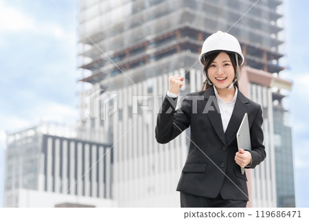 Civil engineering girl: A young woman wearing a suit and helmet and showing her fist in the air; Construction manager; Site supervisor Civil engineering girl: A young woman wearing a suit and helmet and showing her fist in the air; Construction manager; Site supervisor 119686471