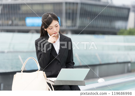 Young businesswoman worried while working on laptop outdoors Young businesswoman worried while working on laptop outdoors 119686998