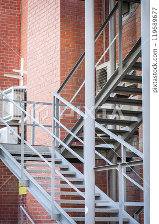 External metal staircase near the red brick wall of the building, emergency exits, vertical format. 119689677