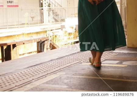 A woman in a skirt walking along the platform of an old train station A woman in a skirt walking along the platform of an old train station 119689876