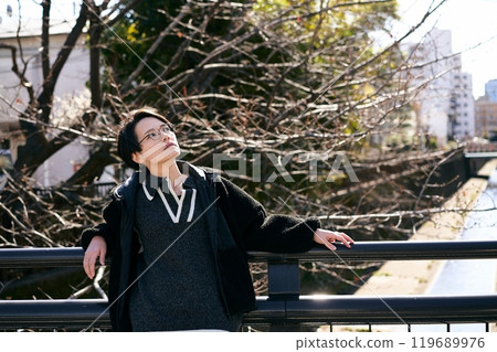 A person leaning on a bridge and looking into the distance 119689976