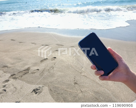 Photo of a woman with a smartphone by the sea Photo of a woman with a smartphone by the sea 119690908