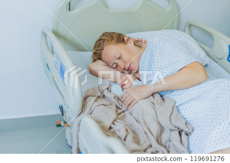 A baby lies with the mother after childbirth, resting peacefully. The serene moment captures the bond between mother and child as they begin their journey together. The hospital environment ensures a 119691276