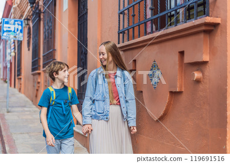 Mother and her son tourists walks through the colonial streets San Cristobal de las Casas, Mexico. Cultural exploration, architecture, and travel experience concept Mother and her son tourists walks through the colonial streets San Cristobal de las Casas, Mexico. Cultural exploration, architecture, and travel experience concept 119691516