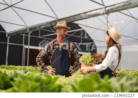 Couple Engaged in Modern Agriculture Inside Greenhouse, Working Together on Sustainable Farming Practices Couple Engaged in Modern Agriculture Inside Greenhouse, Working Together on Sustainable Farming Practices 119692227