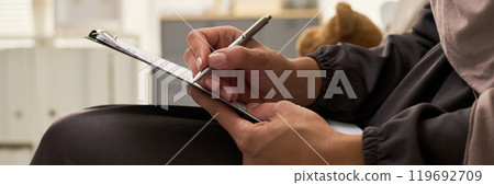 Close-Up of Hands Writing on Clipboard Close-Up of Hands Writing on Clipboard 119692709