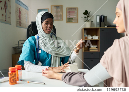 Muslim Female Doctor Checking Patient's Blood Pressure in Clinic Muslim Female Doctor Checking Patient's Blood Pressure in Clinic 119692786