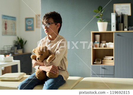 Young Boy Holding Teddy Bear in Modern Room Setting 119692815