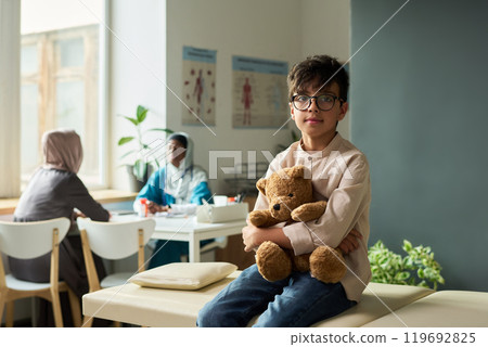 Young Boy Holding Teddy Bear in Medical Waiting Room Young Boy Holding Teddy Bear in Medical Waiting Room 119692825