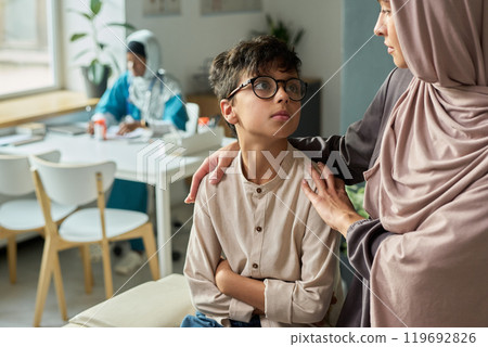 Muslim Woman Comforting Son in Family Living Room Setting Muslim Woman Comforting Son in Family Living Room Setting 119692826