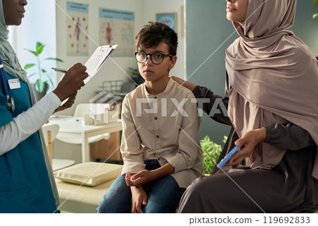 Muslim Doctor Examining Young Boy with Concerned Parent in Clinic 119692833