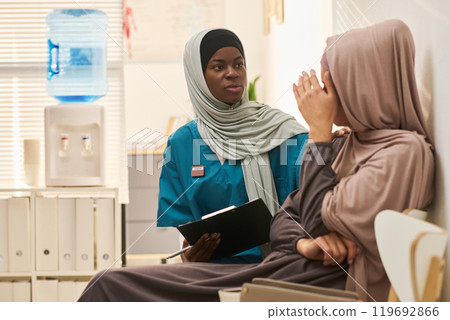 African American Muslim Nurse Comforting Patient in Clinic 119692866