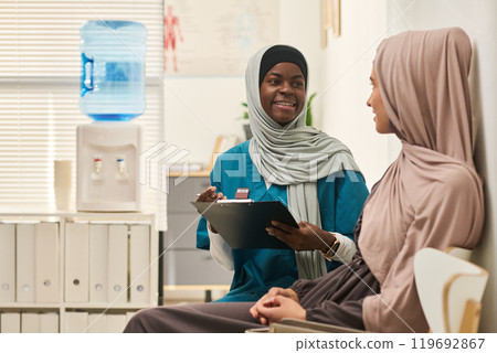Smiling Muslim Healthcare Worker Talking with Patient Smiling Muslim Healthcare Worker Talking with Patient 119692867