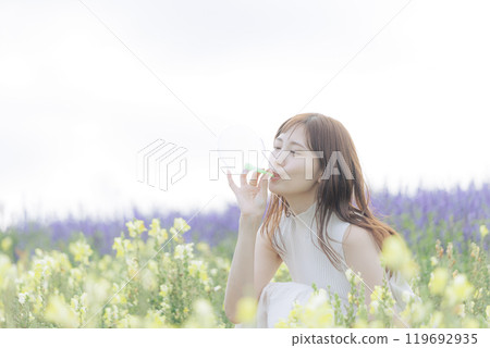 Woman blowing bubbles in a flower field 119692935
