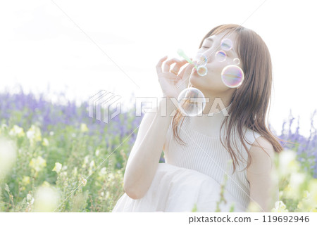 Woman blowing bubbles in a flower field Woman blowing bubbles in a flower field 119692946