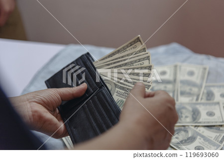 Hand holding money dollar bank note in wallet give financial payment. Man hands showing spread 100 dollar exchange cash in wallet. Saving Businessman counting money banknote bribe corruption concept. Hand holding money dollar bank note in wallet give financial payment. Man hands showing spread 100 dollar exchange cash in wallet. Saving Businessman counting money banknote bribe corruption concept. 119693060