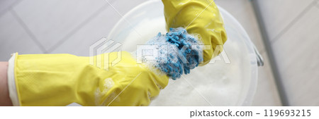 Janitor in rubber gloves wrings mop rag over bucket Janitor in rubber gloves wrings mop rag over bucket 119693215