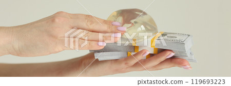 Woman holds silicone breast implants and money in studio 119693223